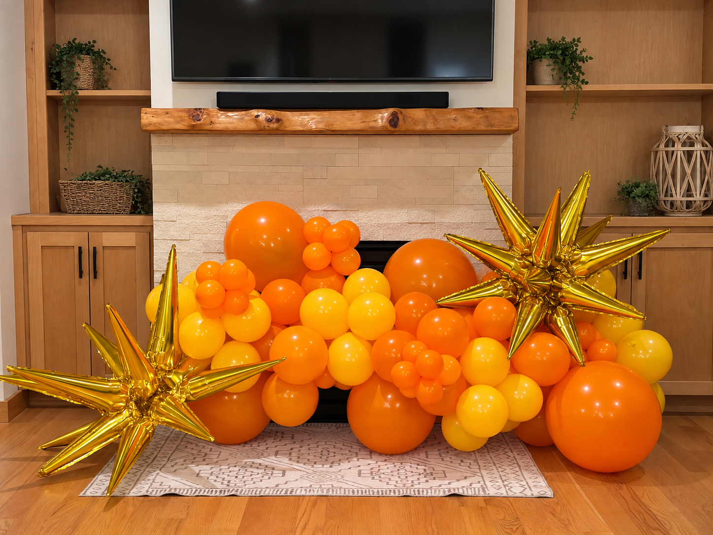 Orange and yellow balloon garland with gold starburst balloons around a fireplace