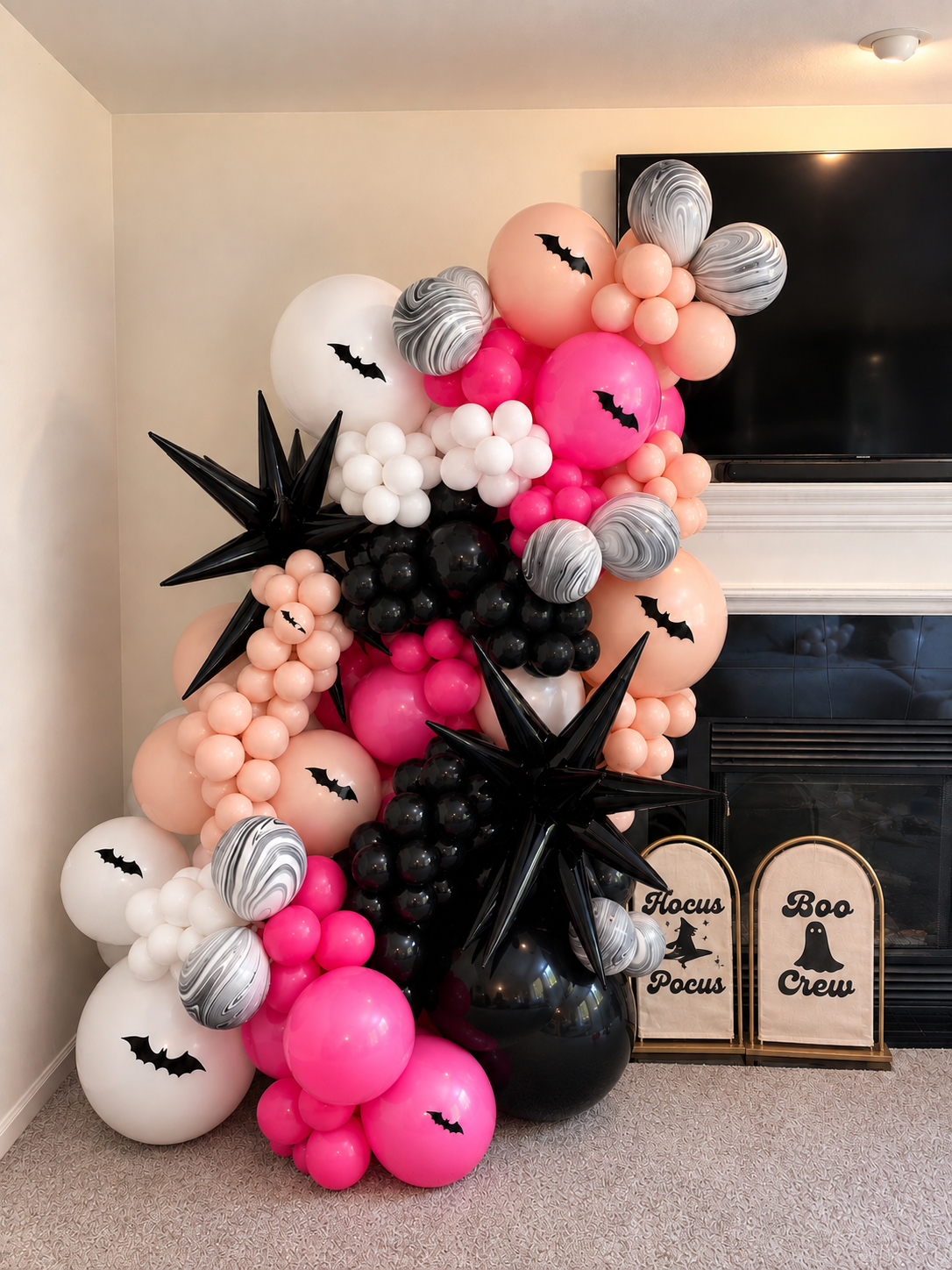 Pink, peach, black and white Halloween balloon installation with bats and starburst balloons
