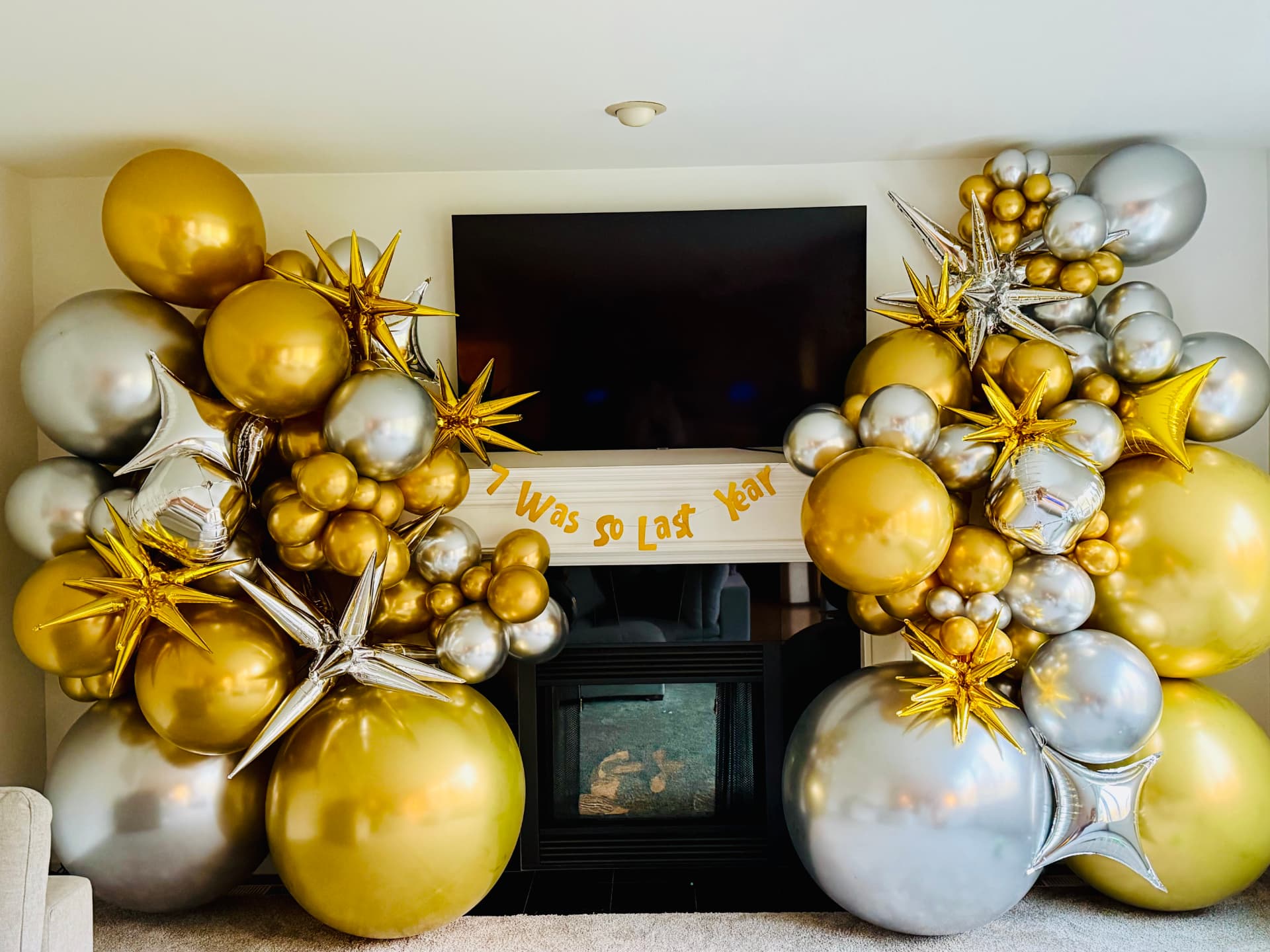Gold and silver balloon starbursts around a fireplace mantel