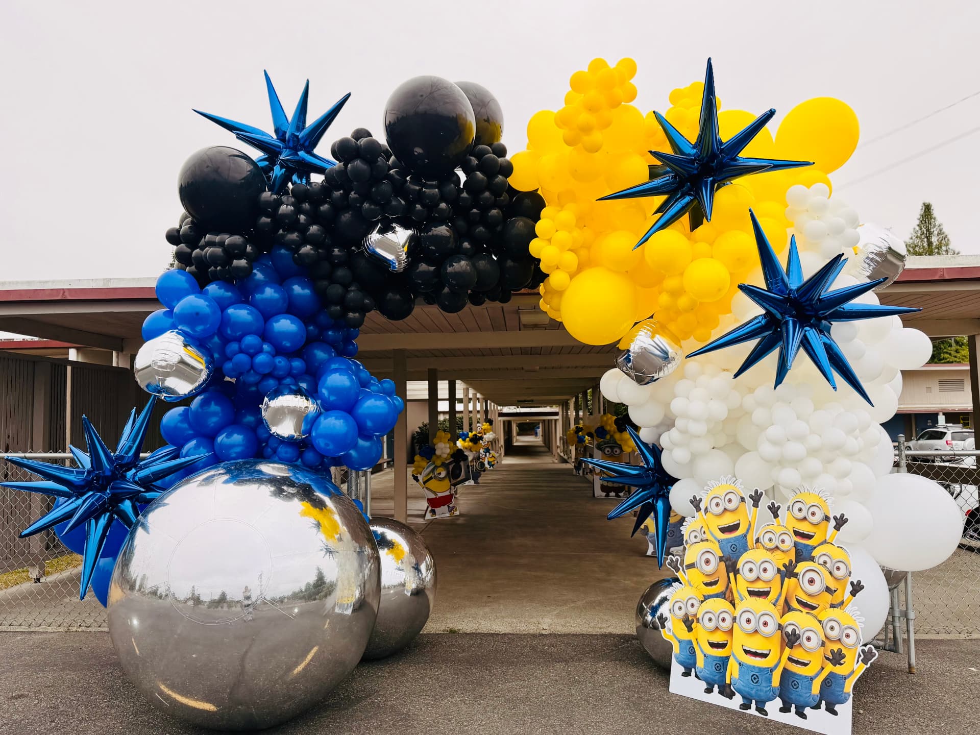 Large yellow and blue Minions balloon arch spanning a school walkway