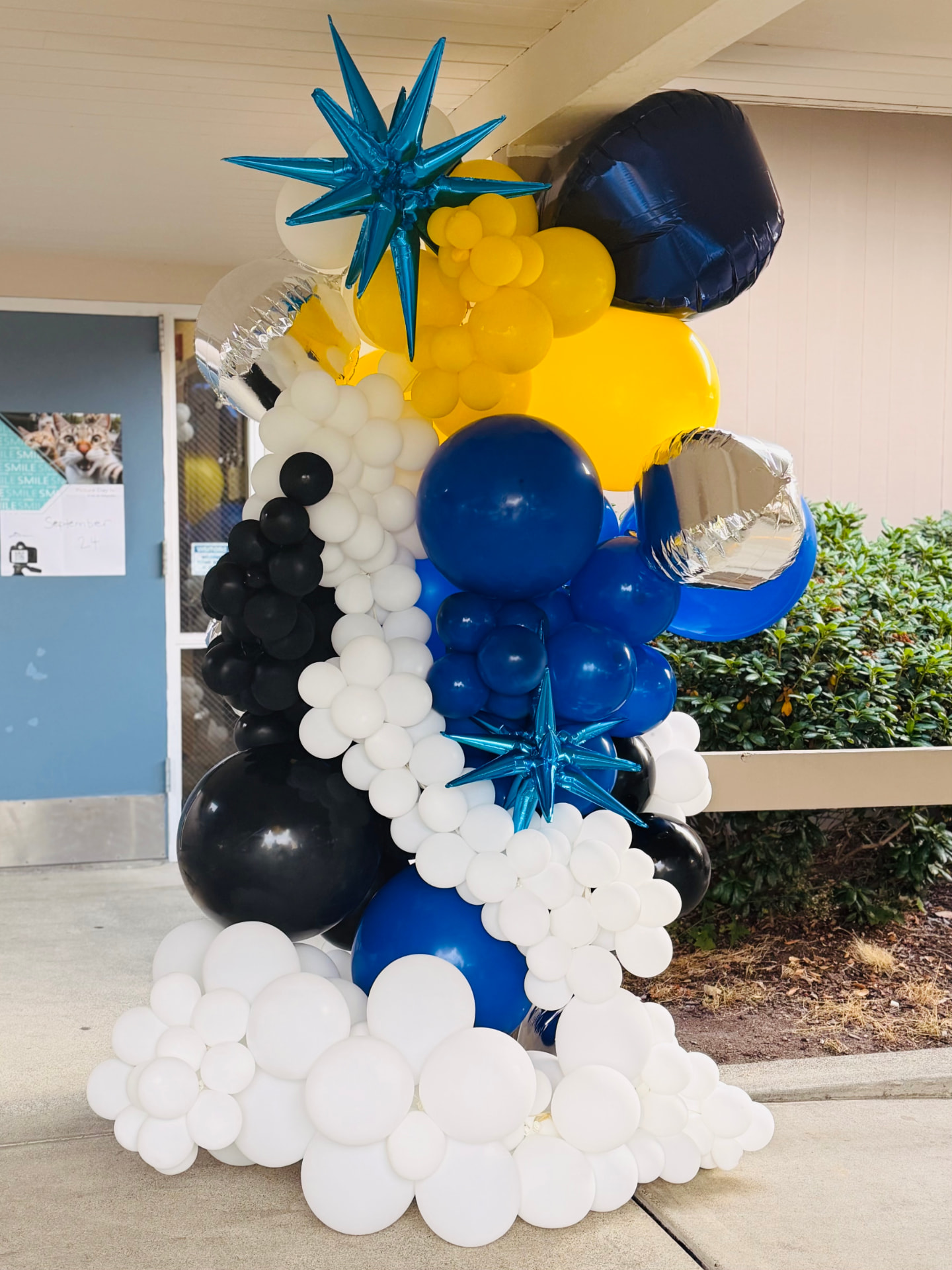 Tall blue, yellow, black and white balloon column with silver starburst accents